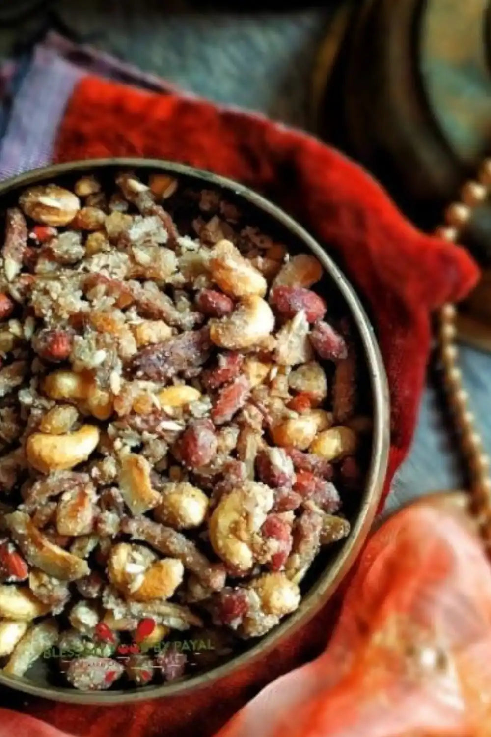 A bowl of mixed nuts and dried fruit, lightly coated with a sweet or savory seasoning.