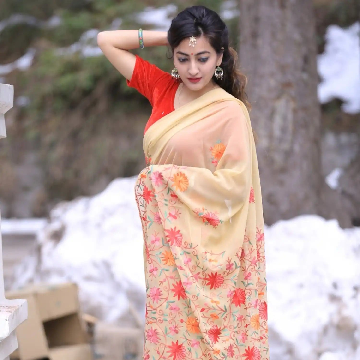 A light-colored saree with vibrant floral embroidery.