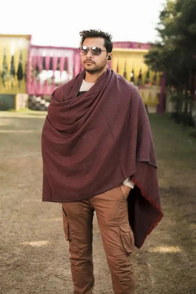 A man wearing a burgundy shawl and brown cargo pants.