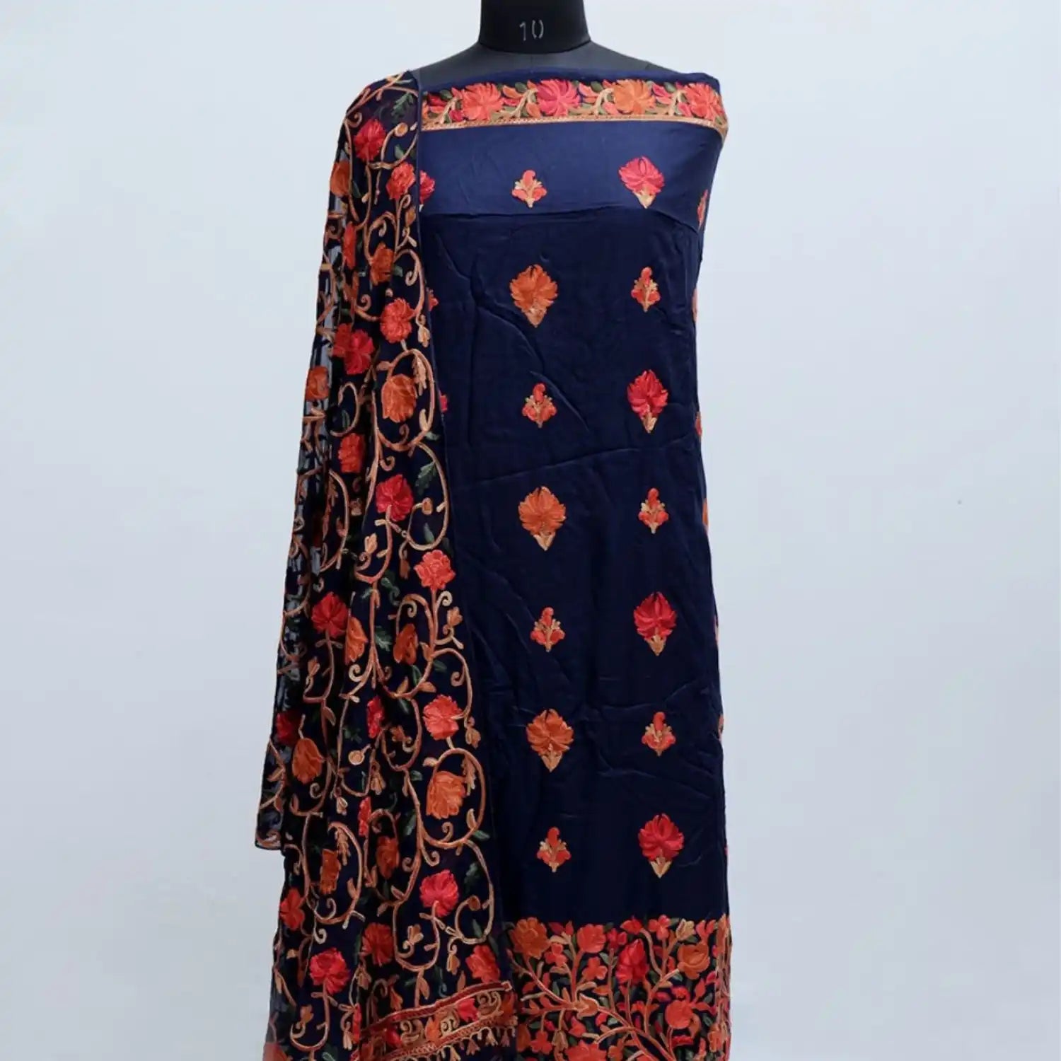A navy blue fabric with intricate orange and red floral embroidery.