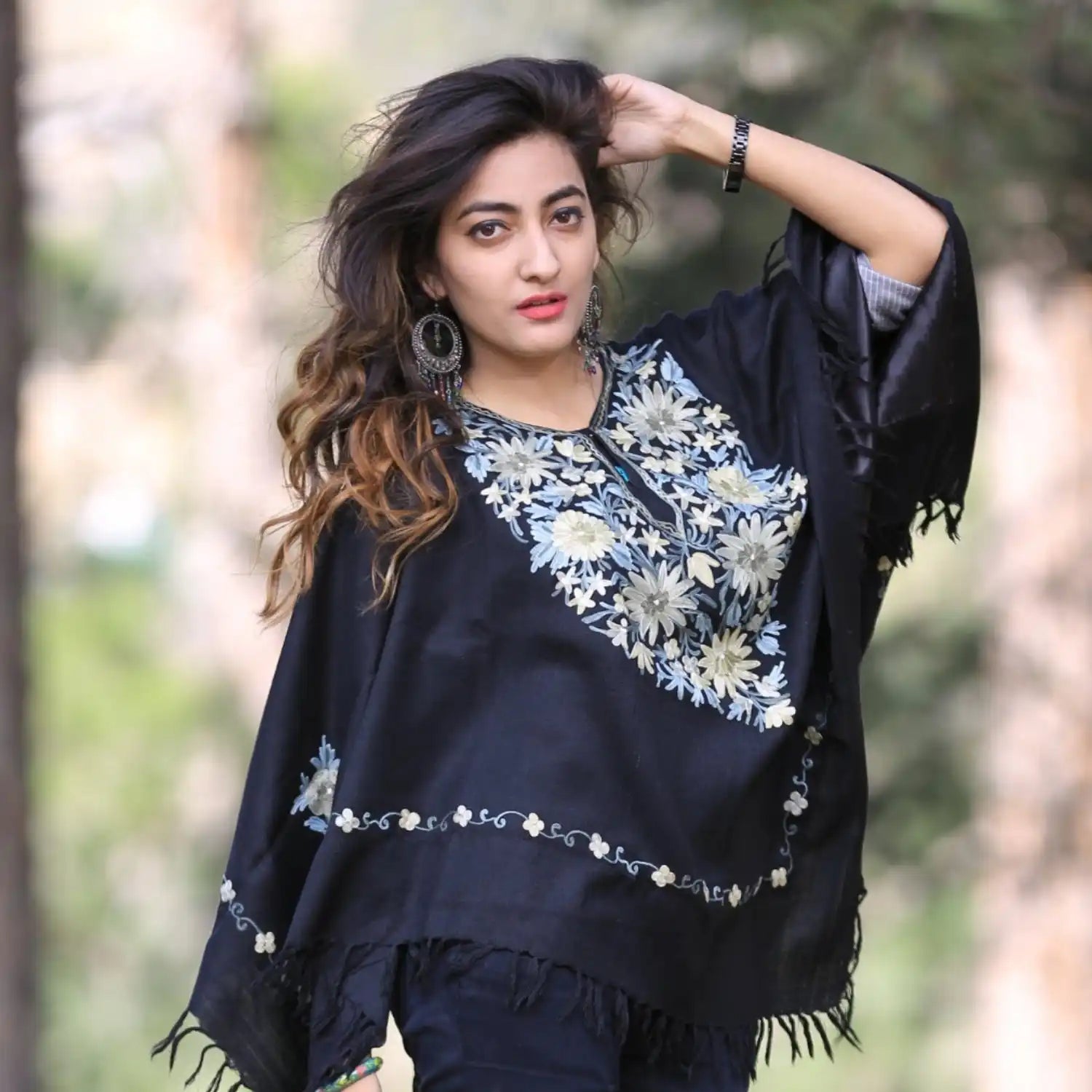 A woman wearing a black embroidered poncho.