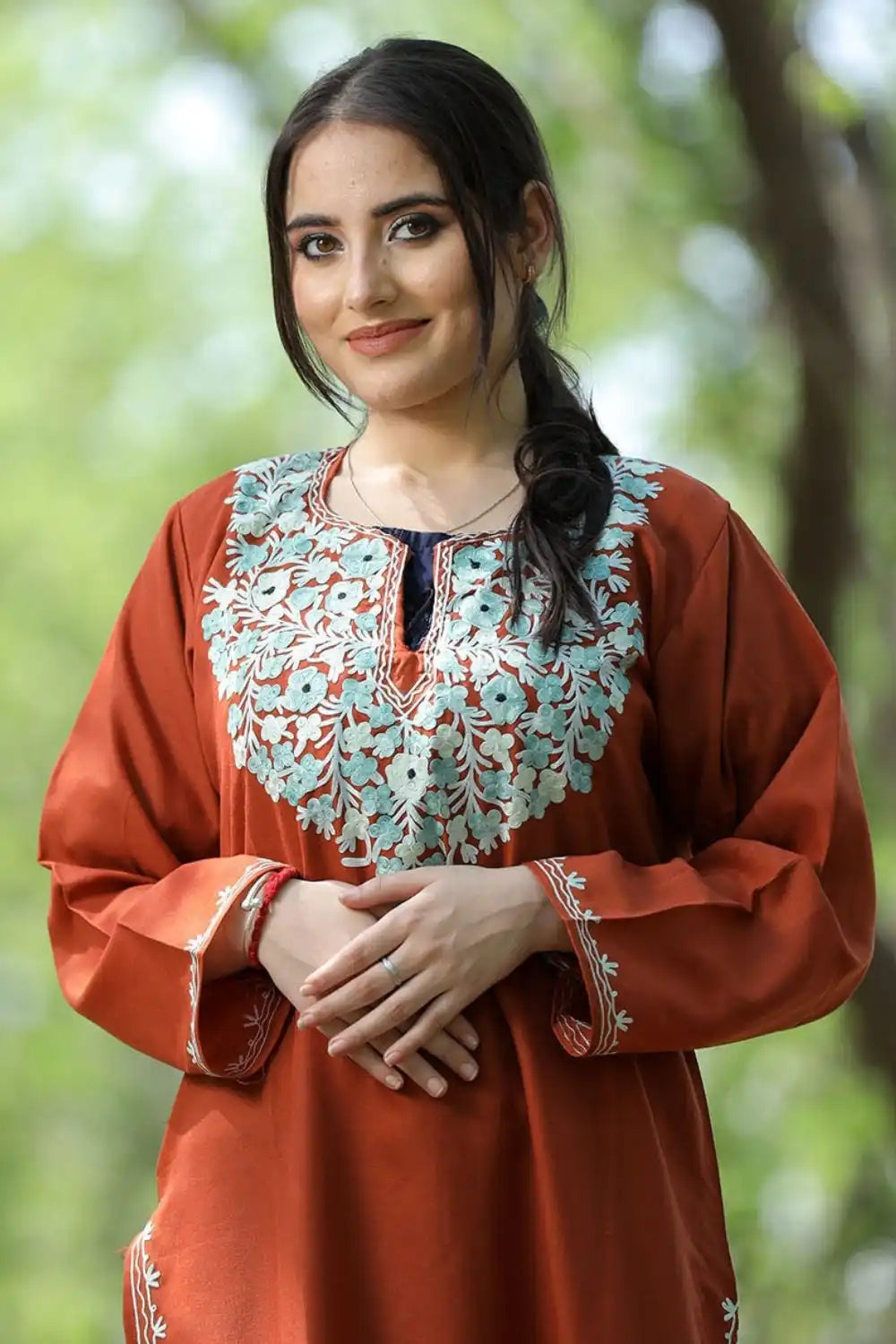 A woman wearing an embroidered terracotta-colored tunic.