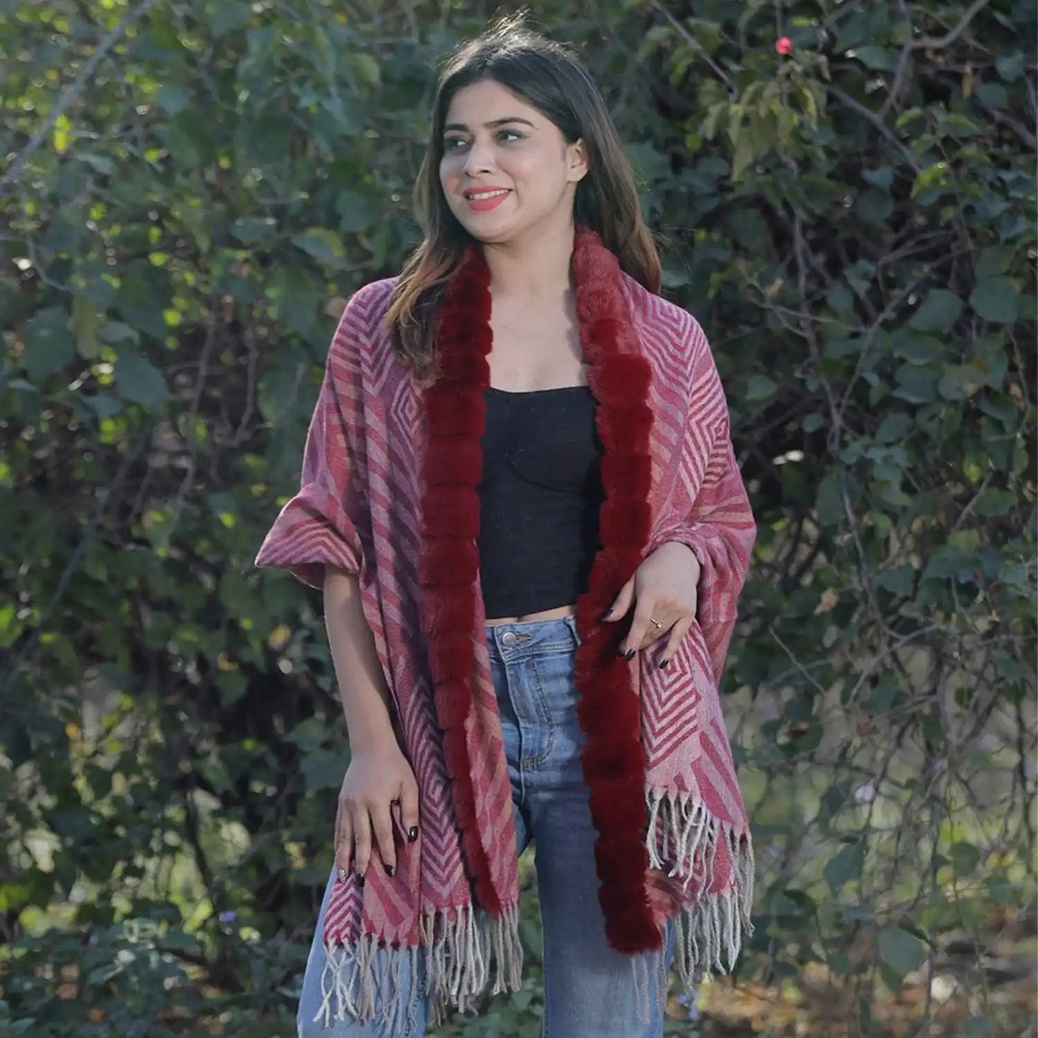 A woman wearing a red patterned shawl with faux fur trim and fringe.