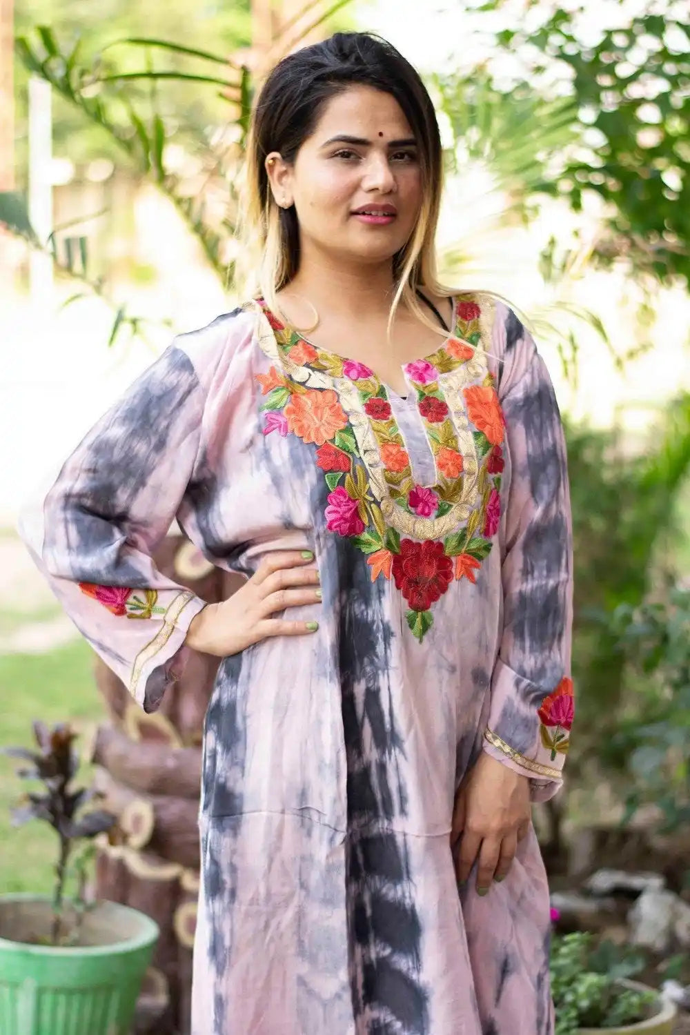 A woman wearing a tie-dye tunic with colorful floral embroidery.