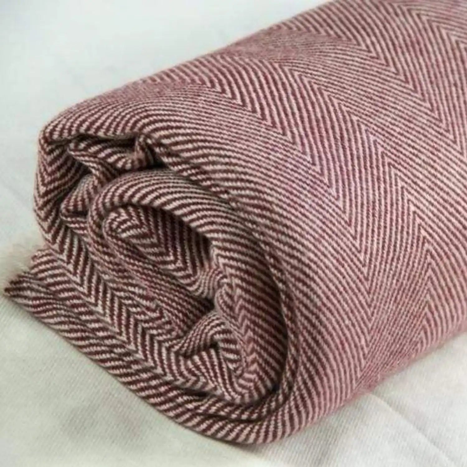 Rolled maroon and off-white herringbone patterned fabric.